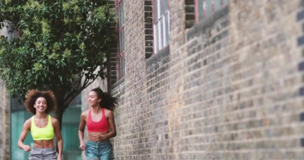 Νεαρή ενήλικο θηλυκό φίλους που τρέχει μαζί σε ένα αστικό περιβάλλον - Πλάνα, βίντεο