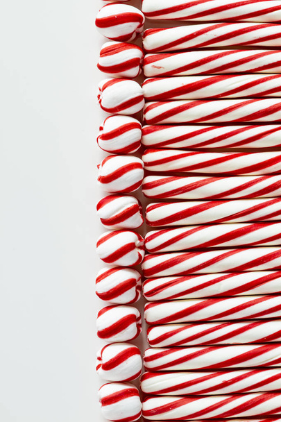 Flat lay background of red and white peppermint sticks and swirled candy balls with blank space on left - Foto, Imagem