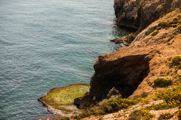 high cliff above the sea, summer sea background, many splashing waves and stone, sunny day - Foto, Imagen