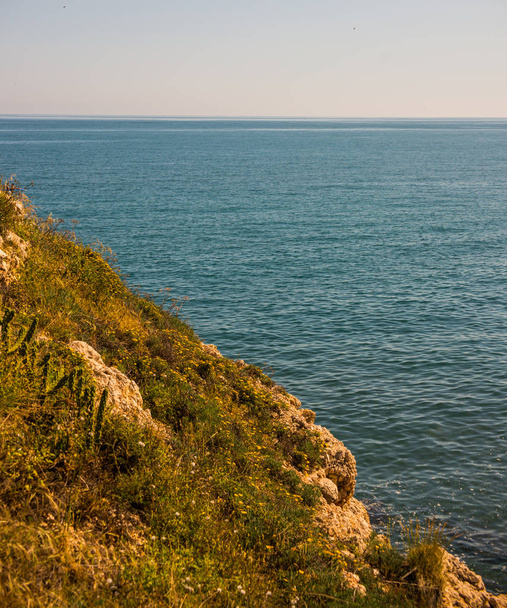 海と夏の海の背景、多くのしぶき波、石、晴れた日の上の高い崖の上 - 写真・画像