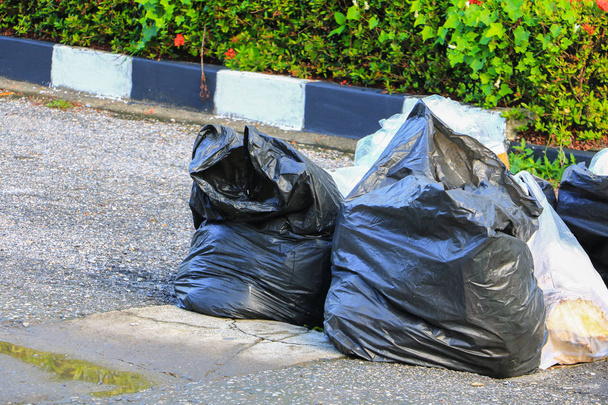 Купа чорних сміттєвих мішків на узбіччі міста
 - Фото, зображення