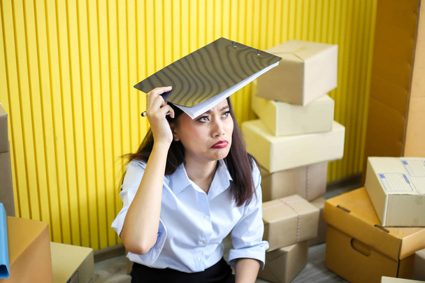 Tired unhappy of   Young asian girl is freelancer Start up small business owner writing address on cardboard box at workplace,Shipping shopping online small business entrepreneur SME or freelance - Фото, изображение
