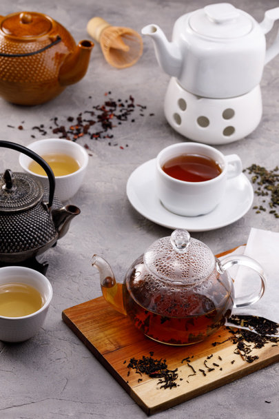 Carta da te '. Diversi in apparenza teiere su uno sfondo grigio, diversi tipi di tè. Tè natura morta. Concetto
. - Foto, immagini
