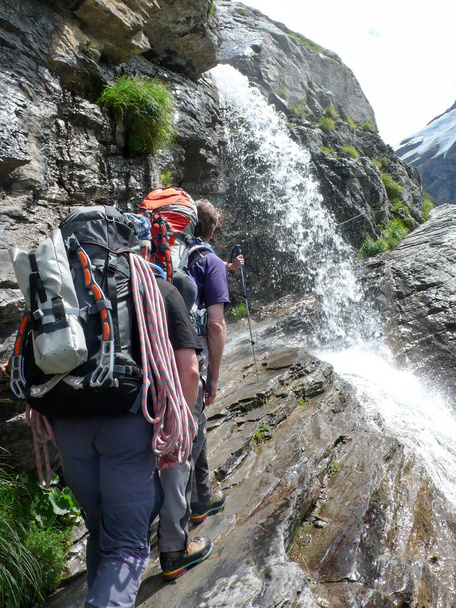 Túrázás a vízesés alatt egy sziklás túraútvonal hegymászók - Fotó, kép