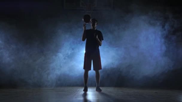 Zamknij nagrania basketball player kulka na jego palcu, ciemny pokój mglisty reflektory - Materiał filmowy, wideo