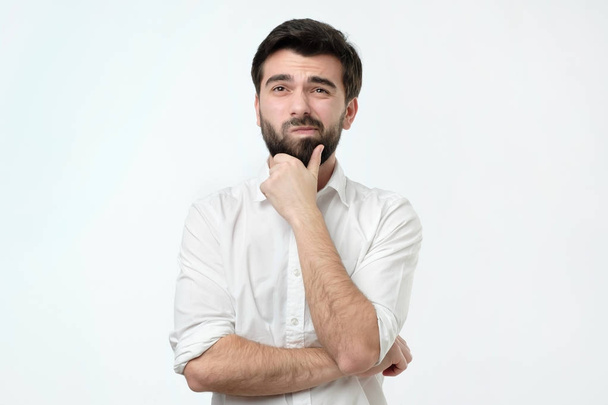 Nadenkend Spaanse man in wit overhemd tegen een witte achtergrond - Foto, afbeelding