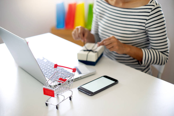 жінка сидить за комп'ютерним столом дивіться на упаковку продукту відкриту або пакувальну тему про покупки онлайн-продажу та замовлення
 - Фото, зображення