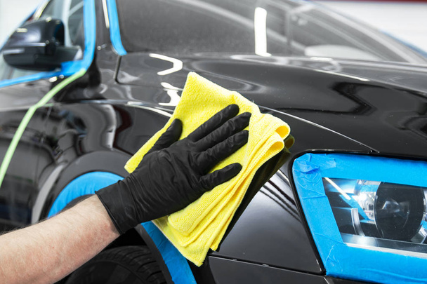 Car polish wax worker hands applying protective tape before polishing. Buffing and polishing car. Car detailing. Man holds a polisher in the hand and polishes the car. Tools for polishing - Foto, afbeelding