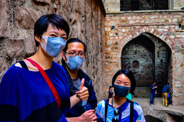 3 Asian tourists wearing masks visiting Ugrasen ki Baoli, a heritage monument in Delhi, India, Circa 2018. Delhi has become an extremely polluted city and it's difficult to breathe even for the locals - Photo, Image