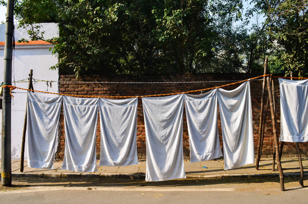  white towels hanging on makeshift tents in streets of central delhi. - Fotografie, Obrázek