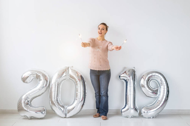 Party, holidays and people concept - Happy young woman celebrating New Year with big 2019 symbol and sparklers - Photo, image