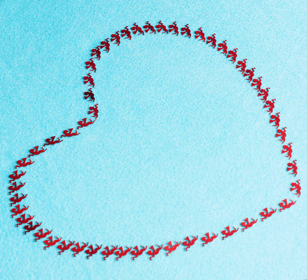 Herzlinien auf blauem Grund sind aus roten Figuren der fliegenden Putten gefertigt. Liebessymbole. Hintergrund für den Valentinstag.  - Foto, Bild