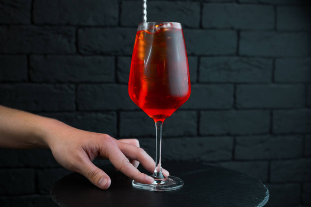 Ο μπάρμαν σερβίρει μια γλυκιά γευστική cranberry κοκτέιλ σε ένα κομψό γυάλινο με την προσθήκη της βότκας με φυσικό χυμό με αμύγδαλο σιρόπι και άσπρο ρούμι. Το ποτό σερβίρεται παγωμένο. Καλό Σαββατοκύριακο νύχτα - Φωτογραφία, εικόνα