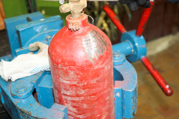 Большой промышленный порок из голубого железа и цилиндр из красного огнетушителя в цехе завода
 - Фото, изображение