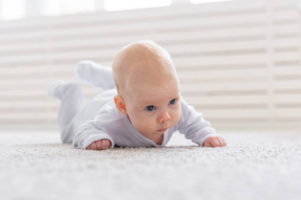 幼年期、乳児および人々 のコンセプト - 赤ちゃん男の子か女の子を家の床の上でクロール - 写真・画像