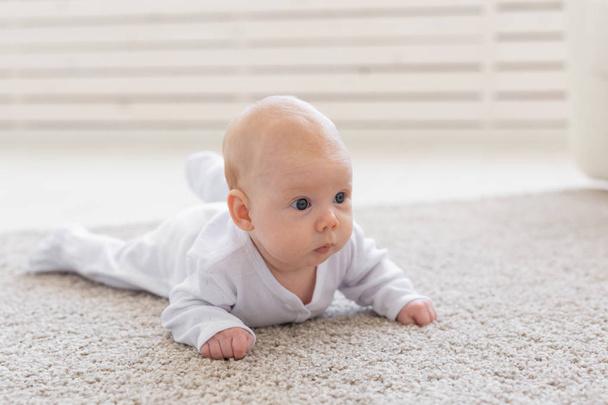 Childhood, babyhood and people concept - little baby boy or girl crawling on floor at home - 写真・画像
