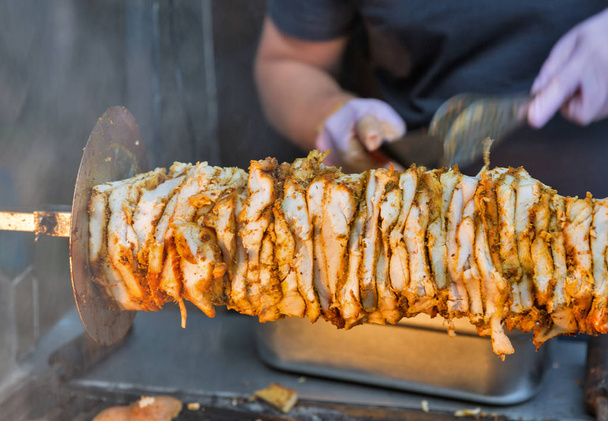 Приготовление шаурмы, мясо слоев нанизано на шампур, рубленое мясо на гриль поверхности, вид спереди
 - Фото, изображение