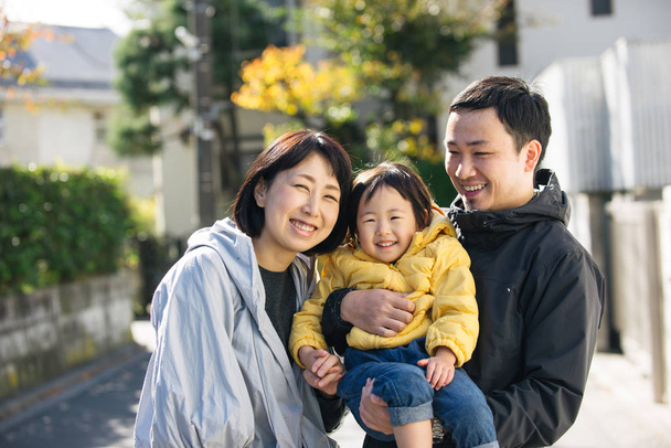 Happy and playful japanese family with small cute daughter having fun outdoors - Fotó, kép