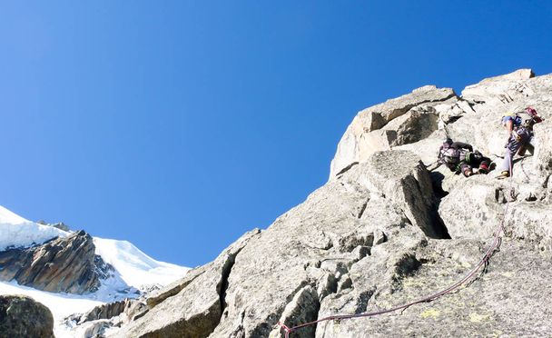 mountain guide looking up on a rocky climb in the French Alps with rope teams ahead of him - Foto, Imagem