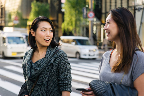 Two girlfriends meeting outdoors and having fun - Japanese people bonding on Tokyo streets - Fotó, kép