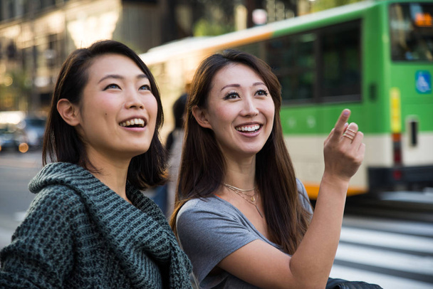 Two girlfriends meeting outdoors and having fun - Japanese people bonding on Tokyo streets - 写真・画像