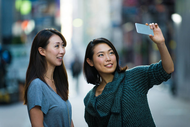 Two girlfriends meeting outdoors and having fun - Japanese people bonding on Tokyo streets - Photo, Image