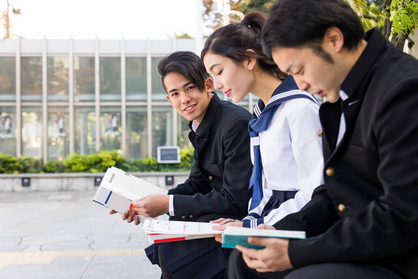 Yung japanese students with school uniform bonding outdoors - Group of asian teenagers having fun - Foto, Imagen