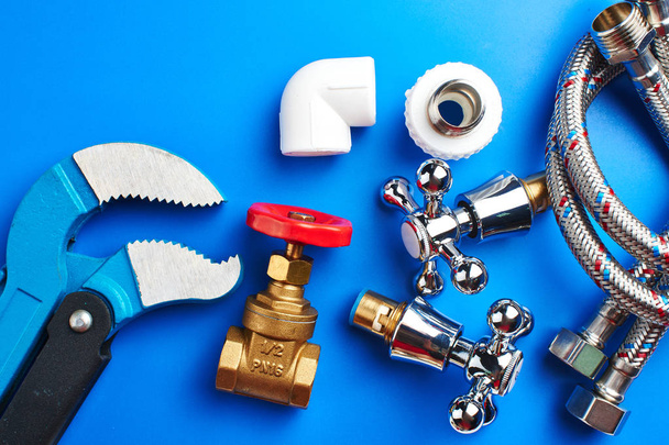 Plumbing parts, accessories and tools on a blue background. - Fotó, kép
