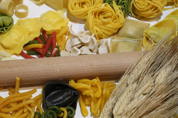 キッチン麺棒と新鮮なイタリア パスタ、小麦の穂をたくさん。大きな黒い raviolo はイカスミで作られて - 写真・画像