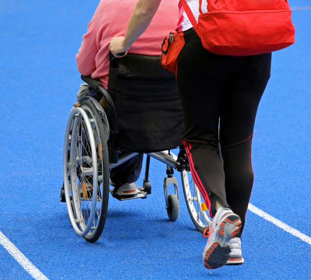 Rollstuhl mit einem Begleiter auf der Leichtathletikbahn - Foto, Bild
