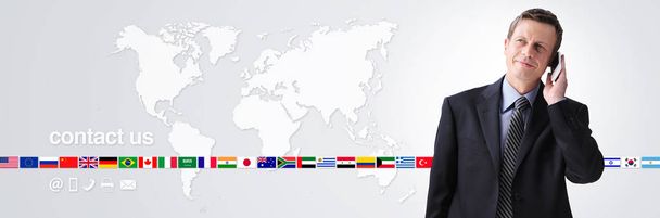international contact us concept, businessman with mobile phone isolated on world map background, flags icons and contact symbols, web banner and copy space template - Photo, Image
