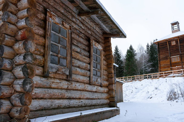 monsters van oude houten architectuur in een winterlandschap - fragment van een logboek-hut en een toren op de achtergrond - Foto, afbeelding