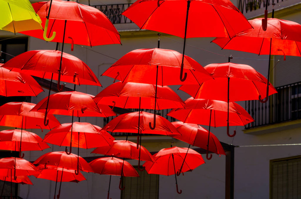 Красочные зонтики для украшения городских улиц. Висящие красочные зонтики над голубым небом, туристическая достопримечательность, солнечный день
 - Фото, изображение