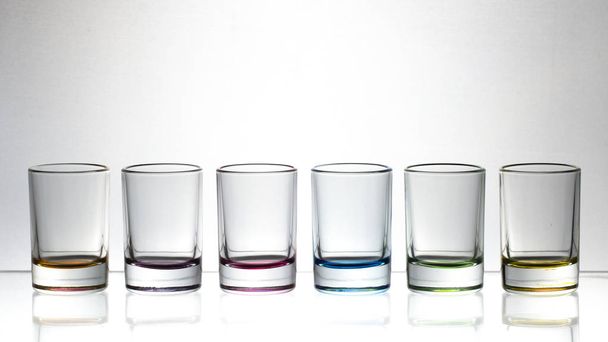 Kuusi pientä moniväristä lasia kirkkaalla taustalla lähikuva
 - Valokuva, kuva