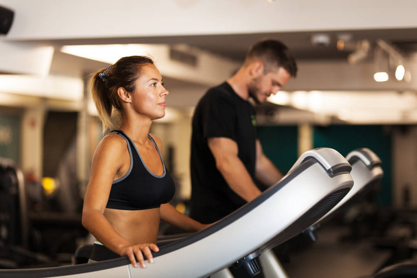 couple working out on a treadmil in a fitness club - Fotó, kép