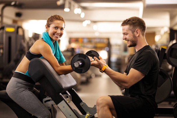 happy girl with fitness coach lifting weights - Zdjęcie, obraz