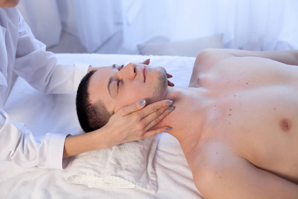 männlicher Masseur bei der Massage des Heilbades für Gesicht und Nacken - Foto, Bild