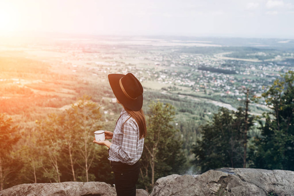 Женщина-путешественница наливает кофе с видом на горный пейзаж на восходе солнца. Концепция приключений активного отдыха на открытом воздухе в горах. Летний лагерь
.  - Фото, изображение