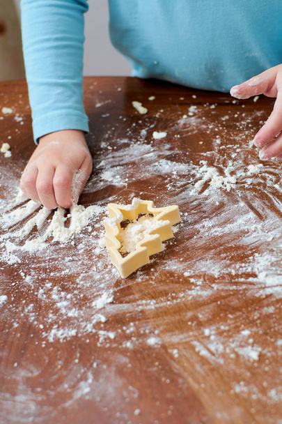 baby making Christmas tree cookies from flour on the table - Valokuva, kuva