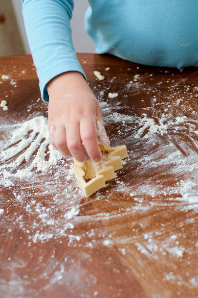 baby making Christmas tree cookies from flour on the table - Zdjęcie, obraz