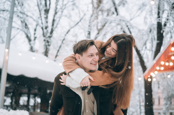 όμορφο νεαρό ζευγάρι έχει τη διασκέδαση σε ένα χιονισμένο δρόμο - Φωτογραφία, εικόνα