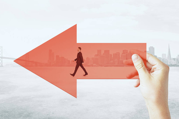 Hand holding red arrow with walking businessman on city background. Growth and startup concept - Photo, Image