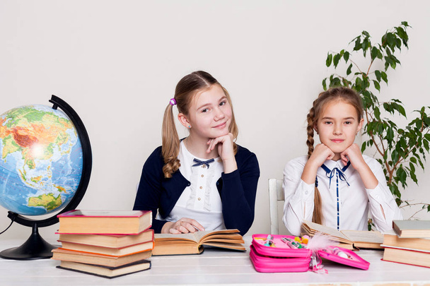 két lány az osztályban tanulni lecke: ő íróasztal globe könyvek - Fotó, kép