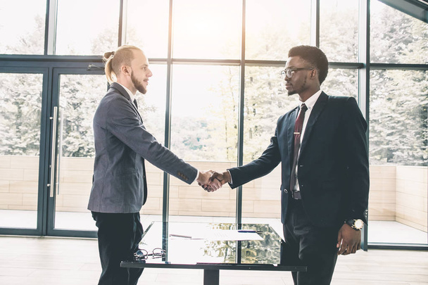 Young Caucasian businessman shaking hands to seal a deal with his partner pretty woman. Multiethnical group of business people having a business meeting - Foto, Imagem