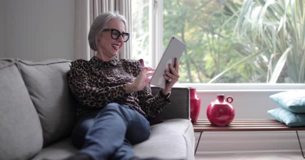 Mature adult female laughing with a digital tablet - Materiaali, video