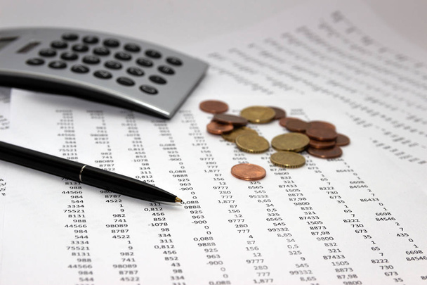 Financiële boekhouding, afbeelding een pluraliteit van getallen op papier en calculator, nummers op papier, een pen en een calculator, munten. - Foto, afbeelding