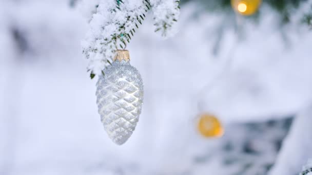 Close-up of a Christmas toy on a snow-covered lively tree in the winter forest on the background of lights. Small DOF - Footage, Video