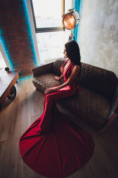 fashion studio photo of gorgeous woman with dark hair and evening makeup, wears luxurious red dress. neon turquoise lights movie spotlight - Foto, afbeelding