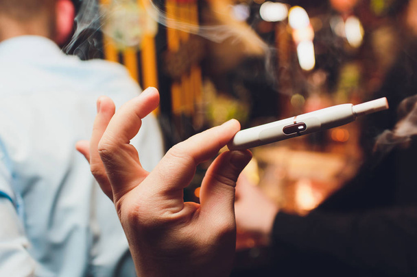 IQOS heat-not-burn tobacco product technology. Man holding e-cigarette in his hand before smoking. - Photo, Image
