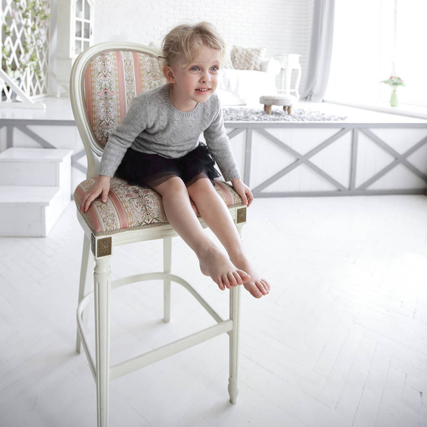 little girl sitting on a chair in a spacious room - Foto, Imagem